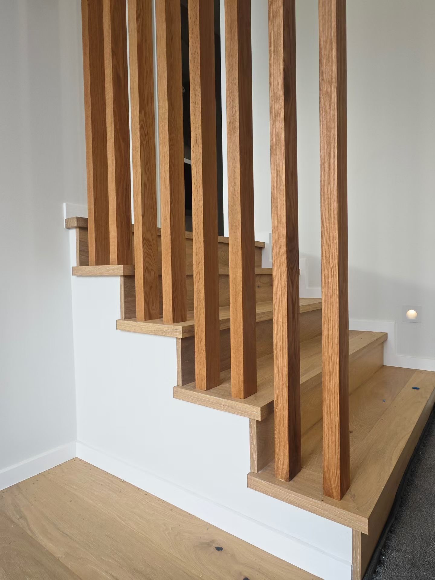 Slat detail at staircase base — each batten individually fitted